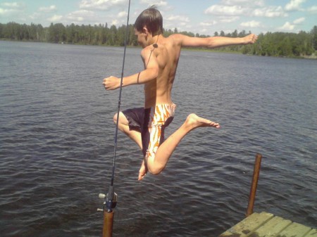 Youngest son jumping off dock at lake house