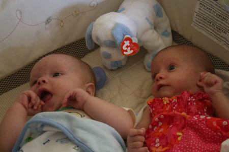 2 little babies sitting in a Pack'n Play...