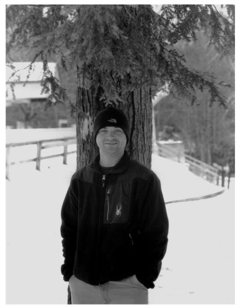 Husband Tom leaning on tree.