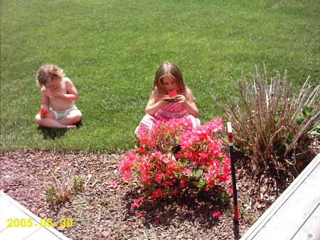 hailey and her cousin amber eating watermelon near a bush that matched at grandmas hosue