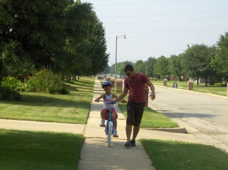 Nicholas (son) teaching Reagan (youngest daughter) to ride her bike