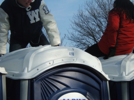 people climbing on port-a-potties