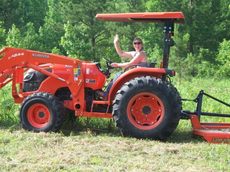 My wife on our tractor in Tennessee