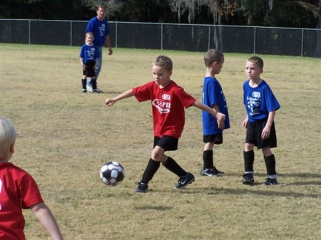 Grandson in red shirt kicking soccer ball