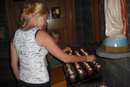 The girls stop to light a few candles