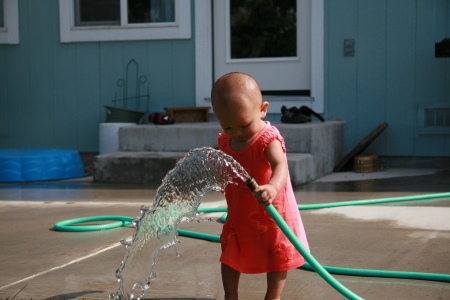 Daughter playing with a garden hose