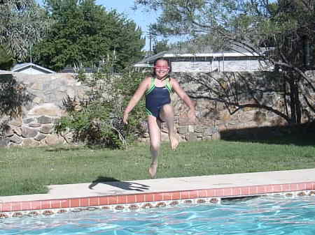 ALICIA DOING A CANNON BALL JUMP IN THE POOL.