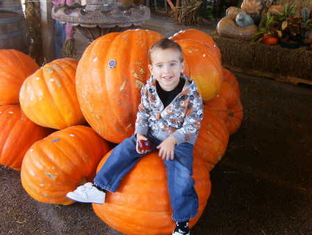 Ryan sitting on the huge pumpkins.