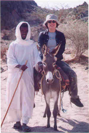 my wife riding a donkey in the desert in Saudi