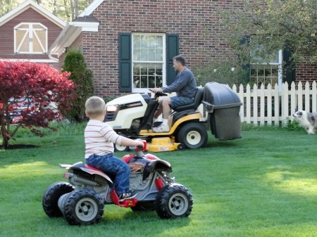 Grandson, Caden & dad cutting lawn.